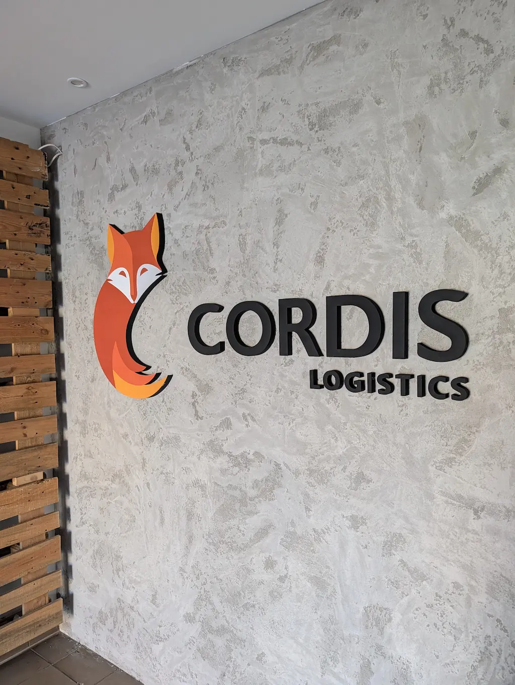 Logo przestrzenne ze styroduru CORDIS LOGISTICS montowane na ścianie z betonu architektonicznego