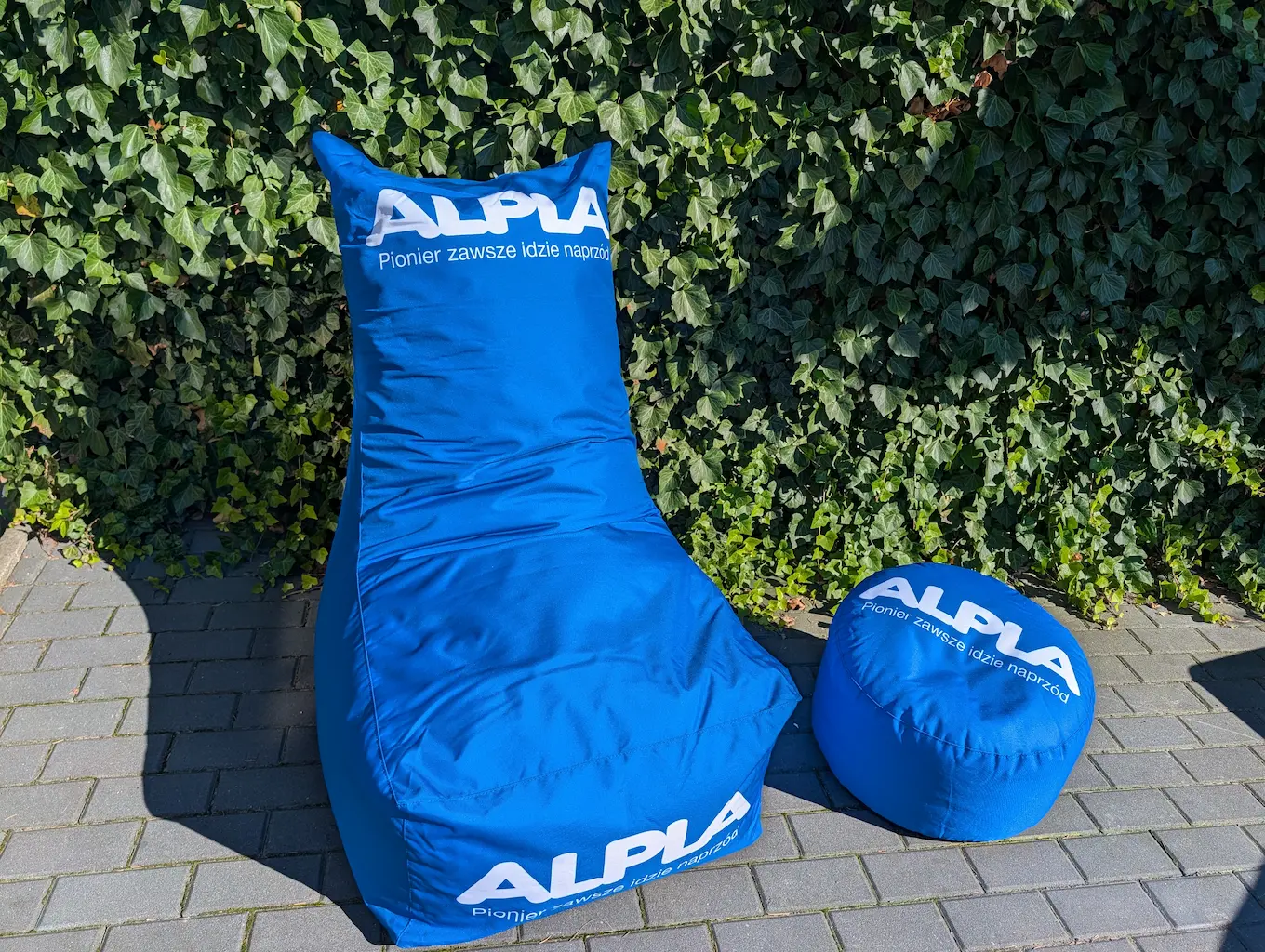 Niebieskie pufy reklamowe i siedzisko z logo ALPLA do strefy chillout
