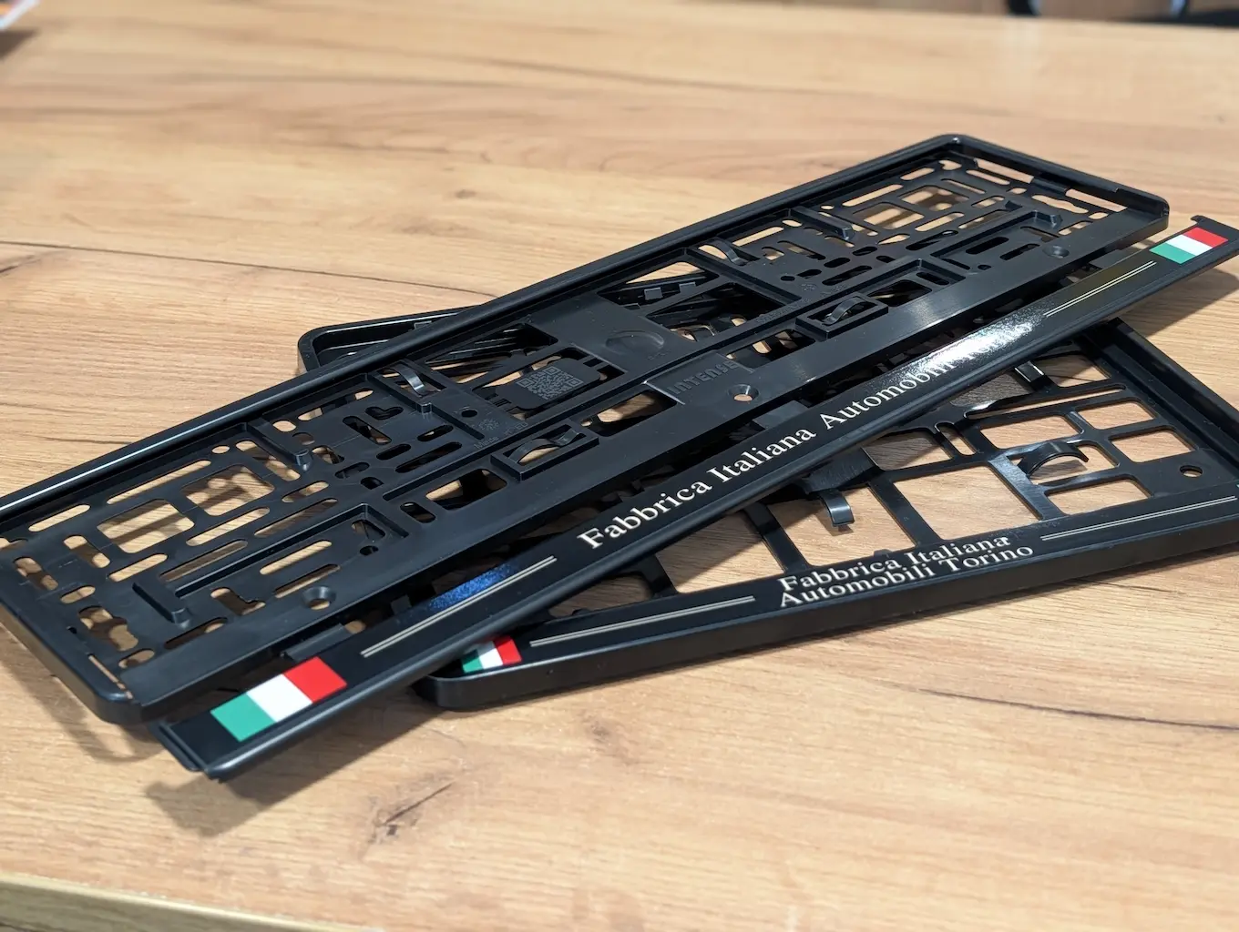 Czarne ramki pod tablice rejestracyjne oklejone folią polimerową z napisem Fabbrica Italiana Automobili Torino i flagą Włoch