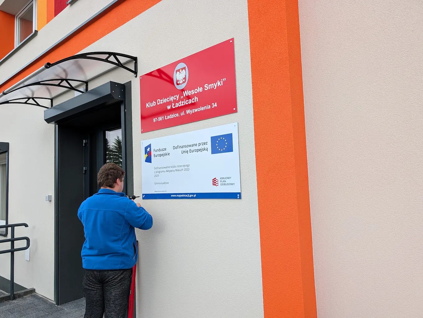 Montaż unijnej tablicy informacyjnej KPO oraz tablicy urzędowej z godłem dla Klubu Dziecięcego Wesołe Smyki w Ładzicach