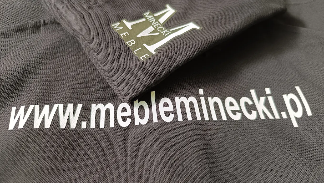 Znakowanie odzieży firmowej folią flex dla Minecki Meble – biały nadruk logo i adresu www na ciemnej tkaninie