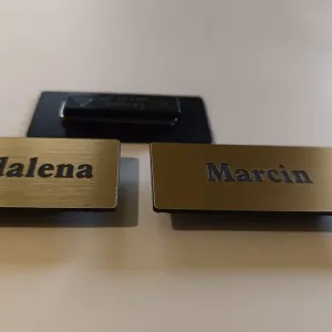 Złote identyfikatory z laminatu grawerskiego z imionami na przypince magnetycznej